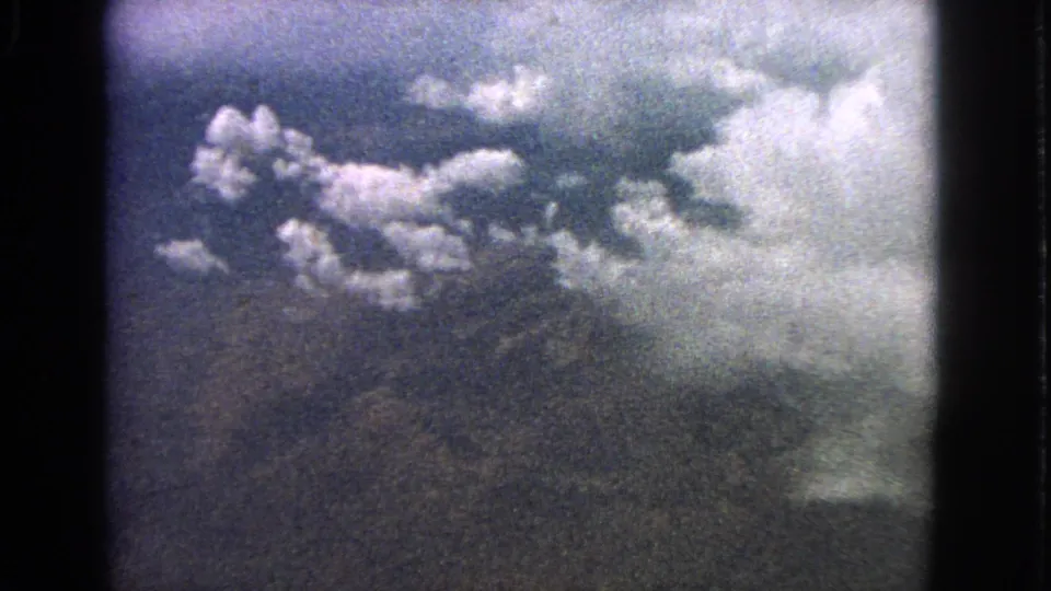 Cataloged 1963 8mm passenger-window view of bright clouds over shadowed terrain.