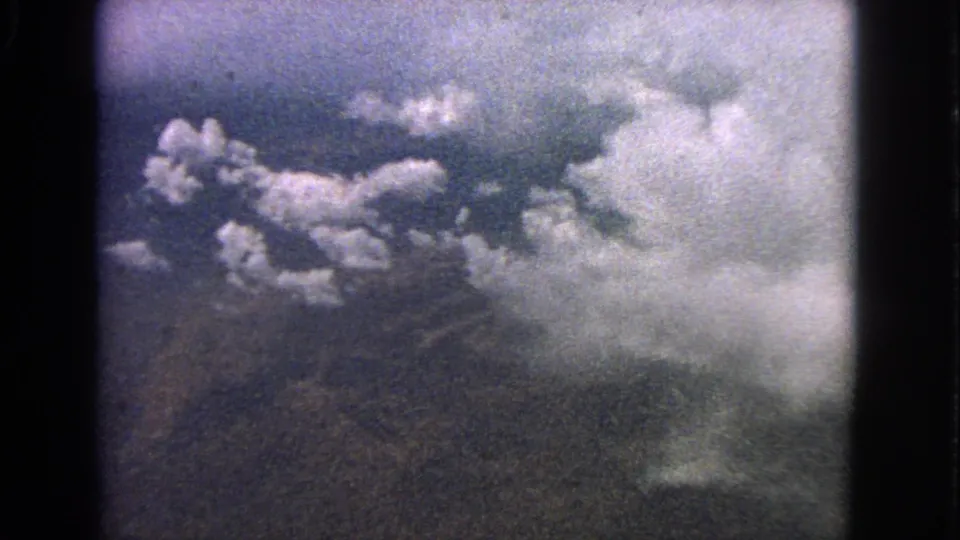 1963 8mm aerial view near Barrington, Illinois, showing scattered clouds over a dark landscape through a window-like frame.