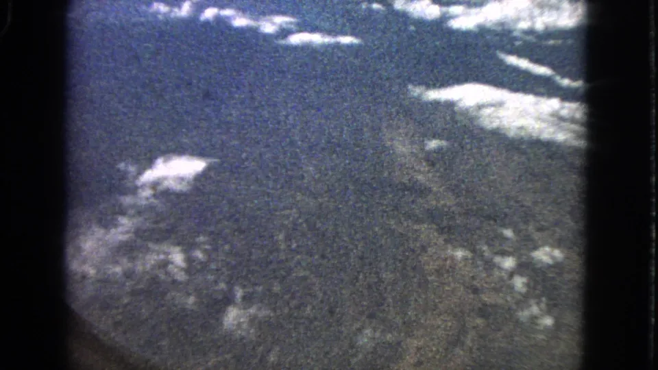 1963 home-movie aerial view near Barrington, Illinois, with clouds, sky, and ground seen through dark frame edges.