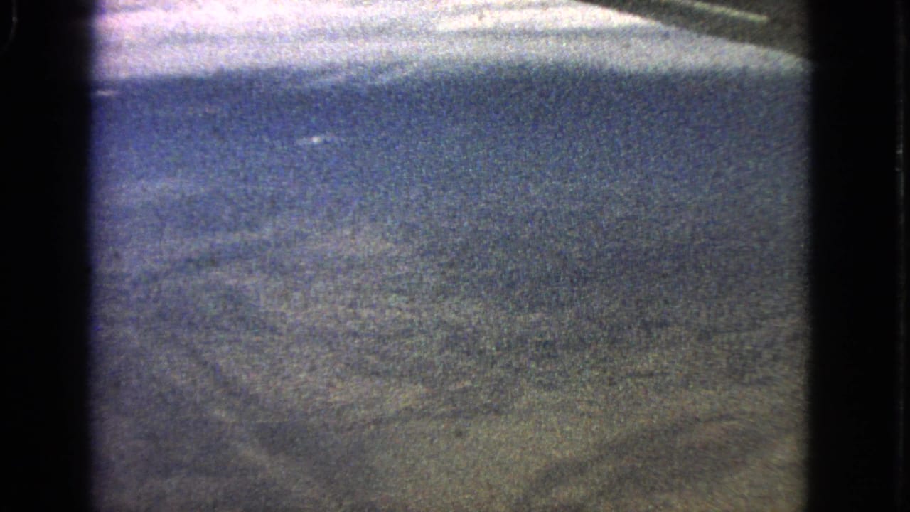 Soft aerial view of textured ground beyond a dark window border.