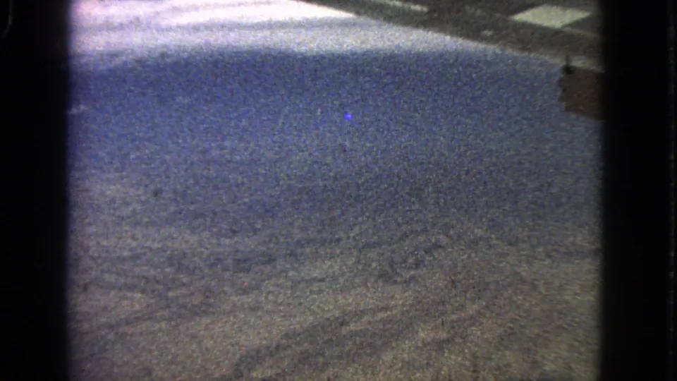 Final 1963 8mm still showing hazy, dry-looking terrain from a passenger aircraft window with strong film grain.