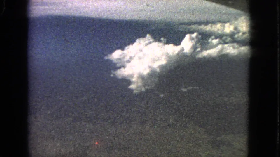 1963 8mm aerial view associated with Barrington, Illinois, showing a cloud cluster above shadowed land and blue sky.