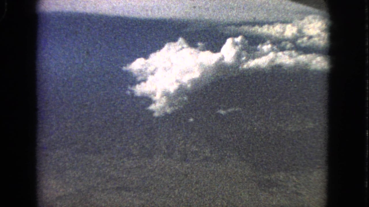 Blue sky and bright cloud mass seen through a rounded 8mm film frame.