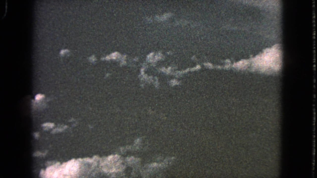 1963 Barrington 8mm frame showing scattered white clouds against a dark, grainy sky with visible film borders.