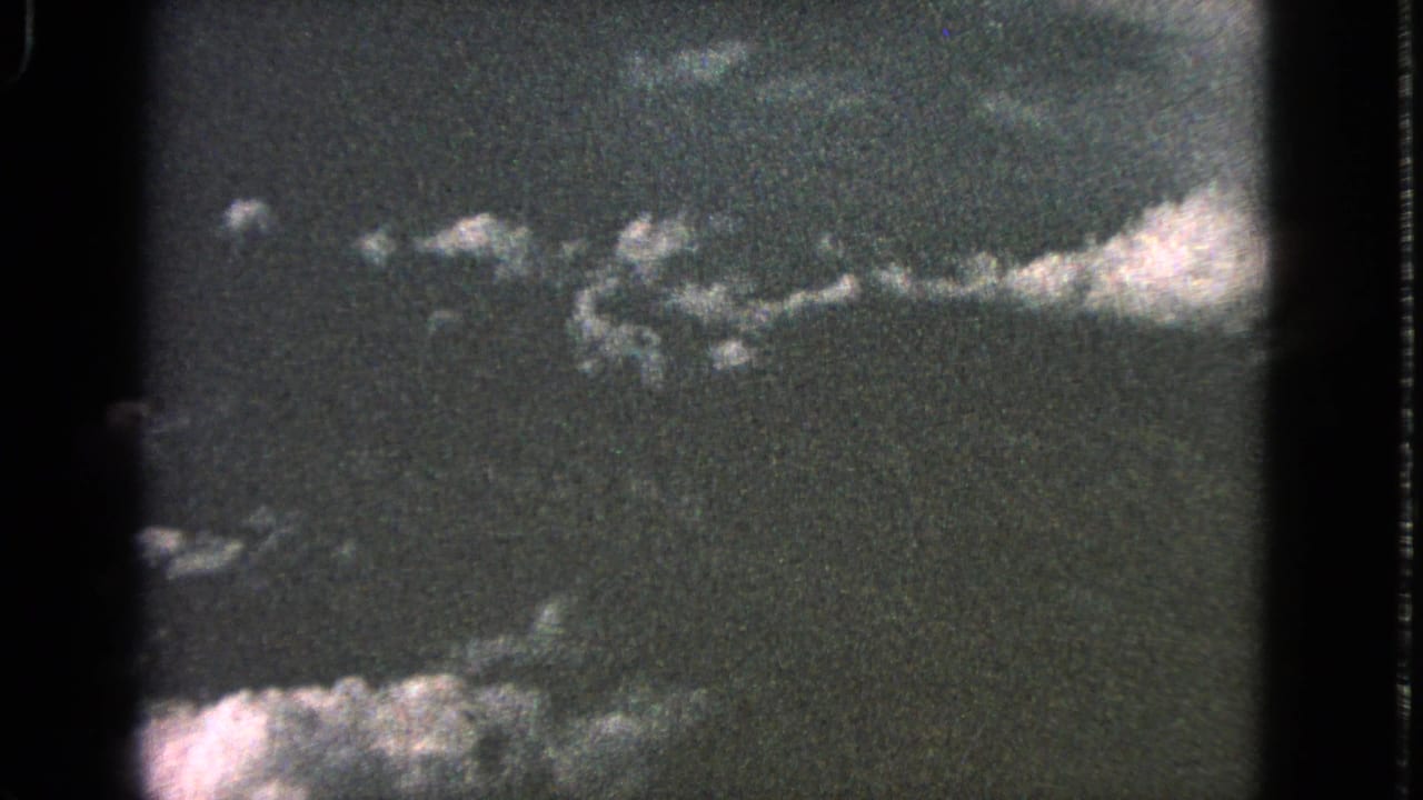 1963 Barrington 8mm sky view with a low band of pale clouds, dark exposure, and rounded film-frame edges.