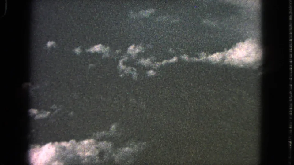1963 Barrington 8mm sky view with a low band of pale clouds, dark exposure, and rounded film-frame edges.