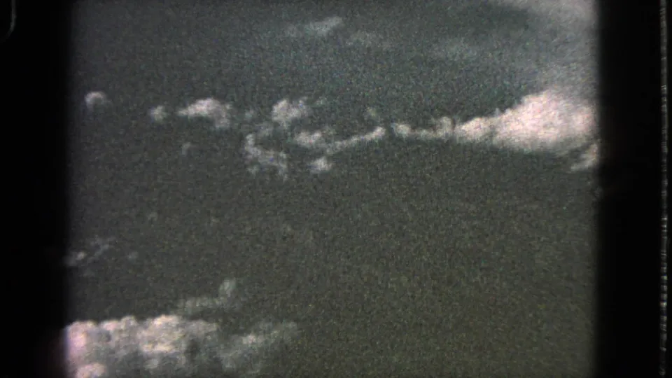 1963 Barrington home-movie sky frame with pale clouds near the lower edge and a darker textured sky above.