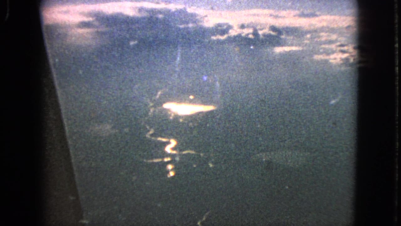 1963 8mm frame from Barrington, Illinois metadata showing a hazy aerial view through an airplane window toward a sunlit winding river.