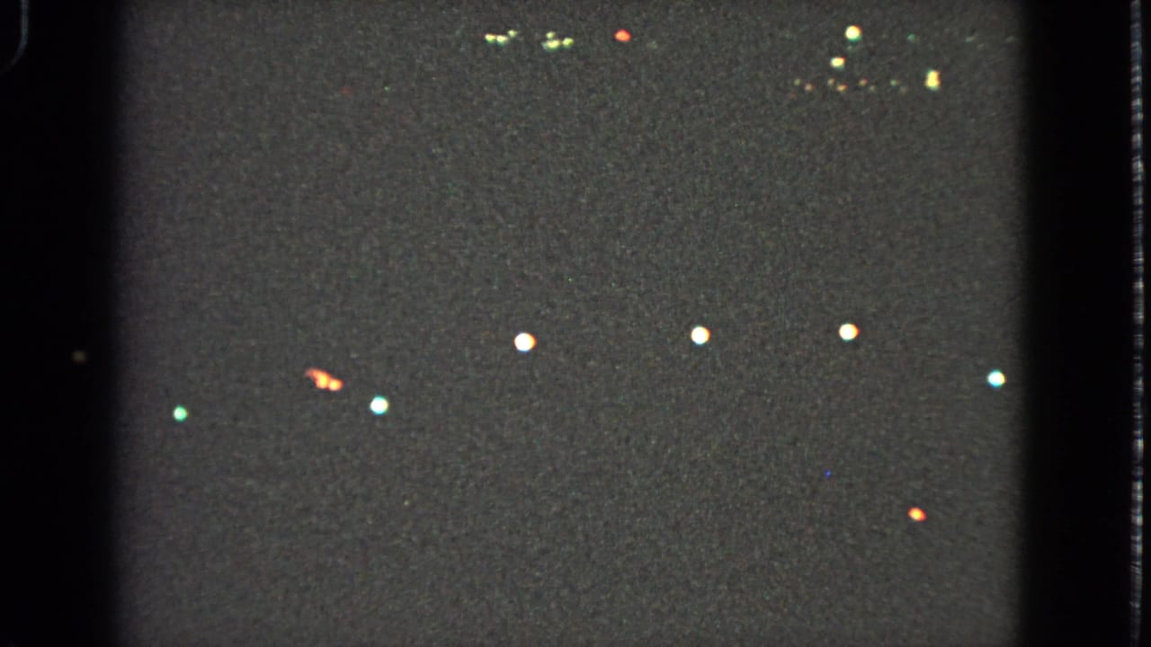 Nighttime Barrington holiday lights appear as distant white, red, and green points in grainy 8mm footage.