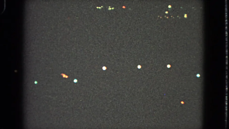 Nighttime Barrington holiday lights appear as distant white, red, and green points in grainy 8mm footage.