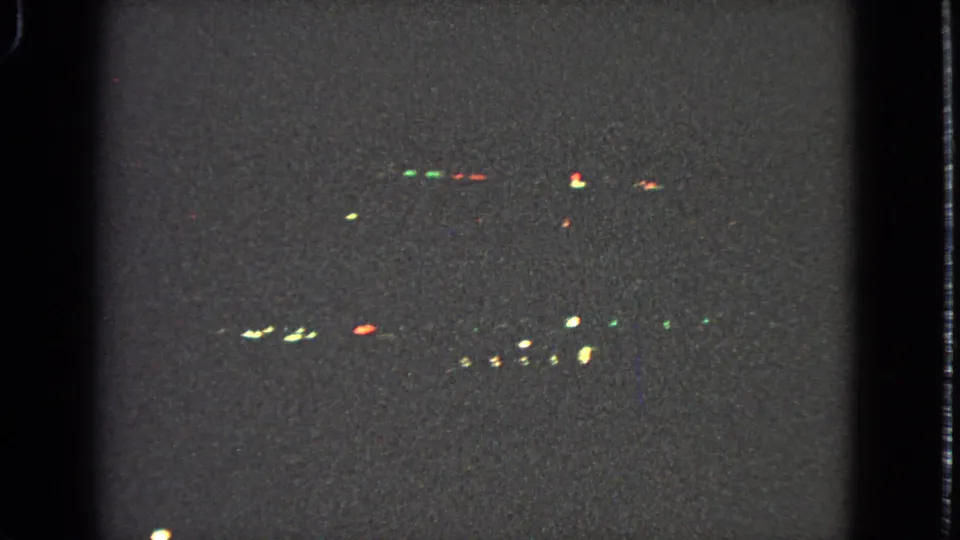 1963 8mm night view from an airplane window near Barrington, Illinois, with small red, green, and pale lights against a dark frame.