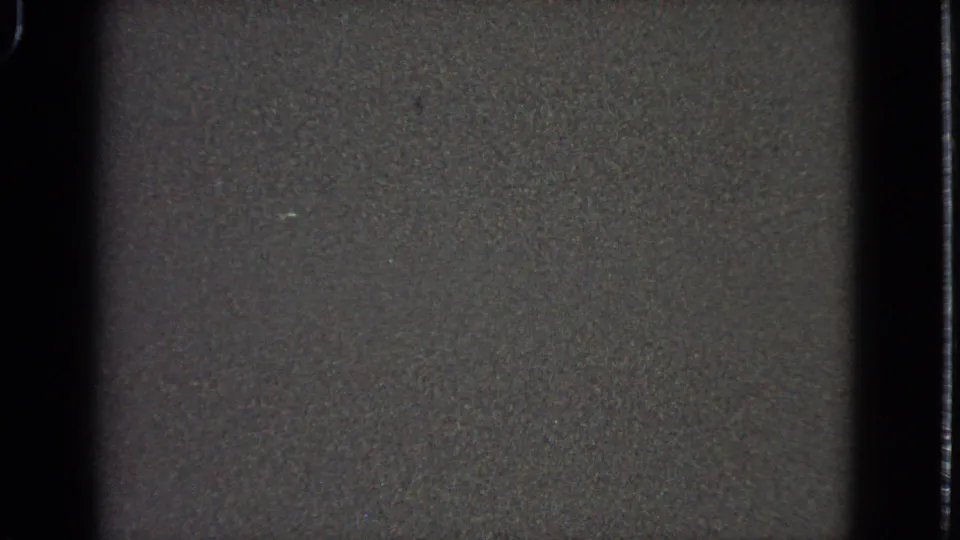 1963 home-movie frame from an airplane window, with scattered runway or city lights and dark 8mm frame edges.