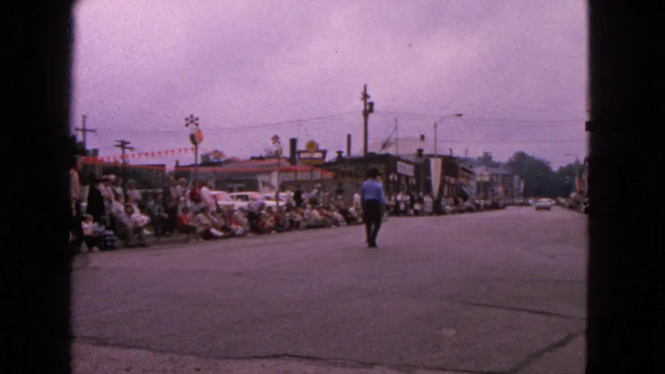 Wide Barrington street view shows parade spectators lining the curb while a man walks along the open roadway.