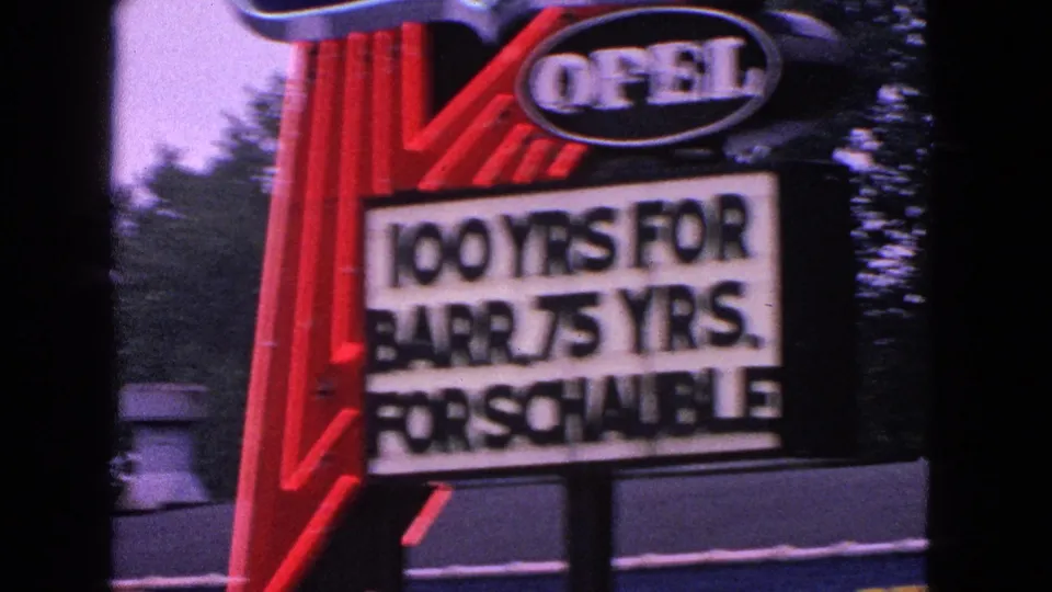 1963 Barrington, Illinois 8mm frame showing a red Opel sign and marquee mentioning Barrington and Schauble anniversaries.
