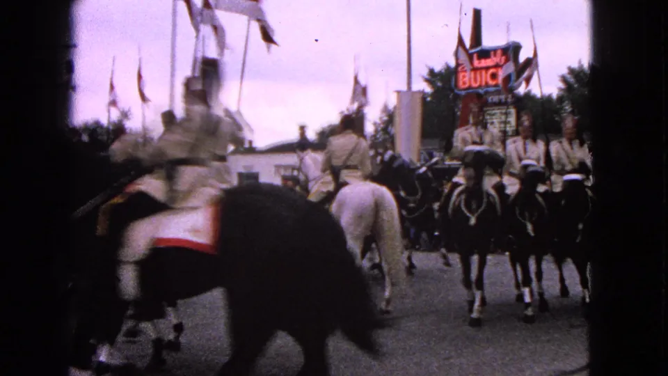 Mounted procession in Barrington, Illinois, with riders on dark and white horses passing a Schwab's Buick sign in 1963 footage.