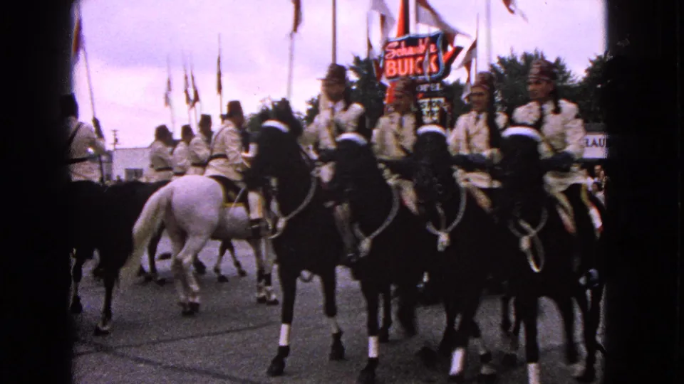 Horseback riders in light uniforms proceed through a 1963 Barrington parade with the Schumacher Buick sign visible behind them.