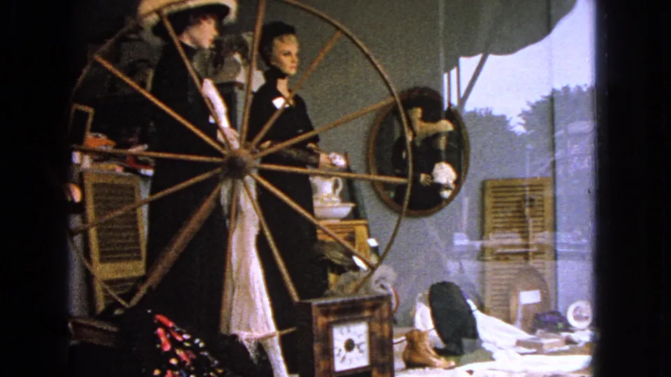 Closer 1963 view of the Barrington shop window, showing dressed mannequins partly obscured by a large wooden spinning wheel.