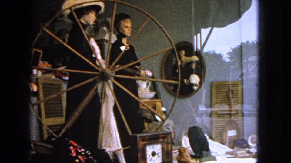Final frame of the 1963 Barrington storefront display, with mannequins and a spinning wheel seen through reflective glass.