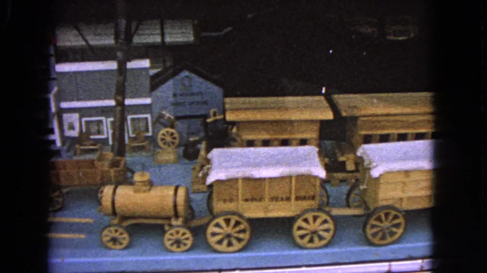 A closer 8mm view shows miniature covered wagons, a small engine, and partial model buildings in the Barrington display.