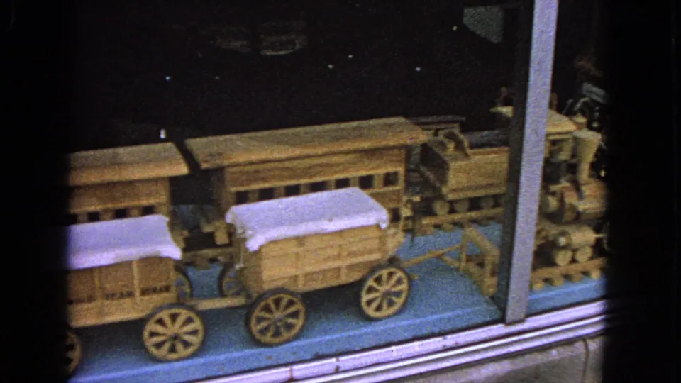 The 8mm pan moves across wooden wagons and a glass divider in the Barrington toy train display.