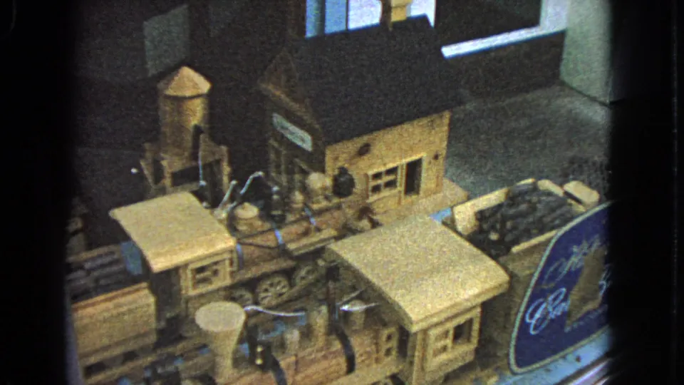 1963 Barrington, Illinois 8mm still showing a wooden toy railroad scene with station, tower, and track.