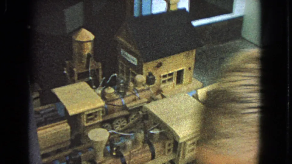 1963 Barrington, Illinois frame of the wooden train display, partly obscured by glass reflection and motion blur.