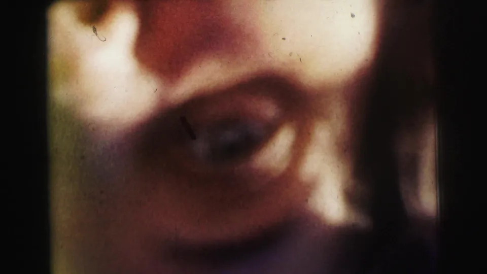 Extreme close-up from the 1963 Bowling Green University home movie showing a shadowed face near the camera, softened by grain and film wear.