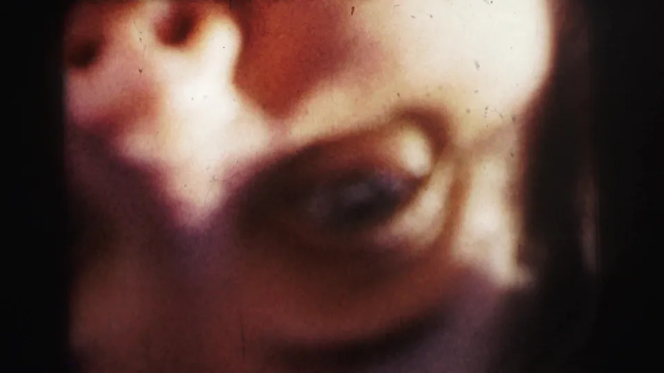 A second extreme close-up in the 1963 Bowling Green University reel shows a face pressed near the lens, with soft focus, shadow, and scratched color film texture.