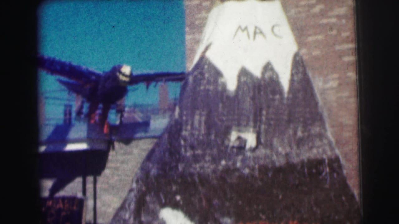 Painted mountain with MAC lettering and a dark bird figure partly visible at left.