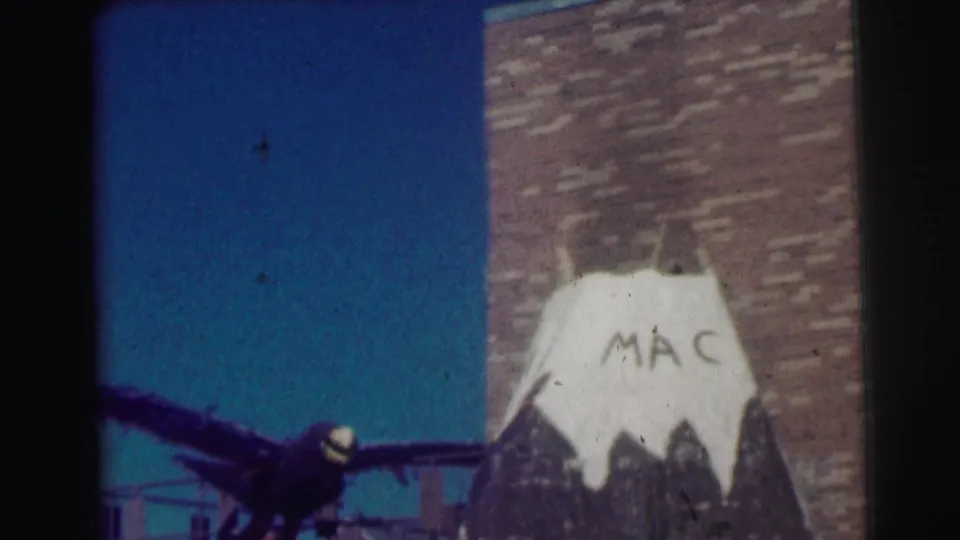 1963 Bowling Green University frame with the painted mountain display cropped low, MAC lettering visible, and blue sky beside a brick wall.