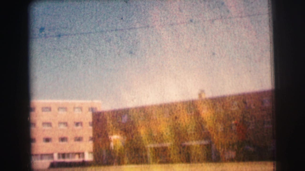 Bowling Green University exterior appears in a warm, scratched 1963 8mm frame with a long facade and open sky.