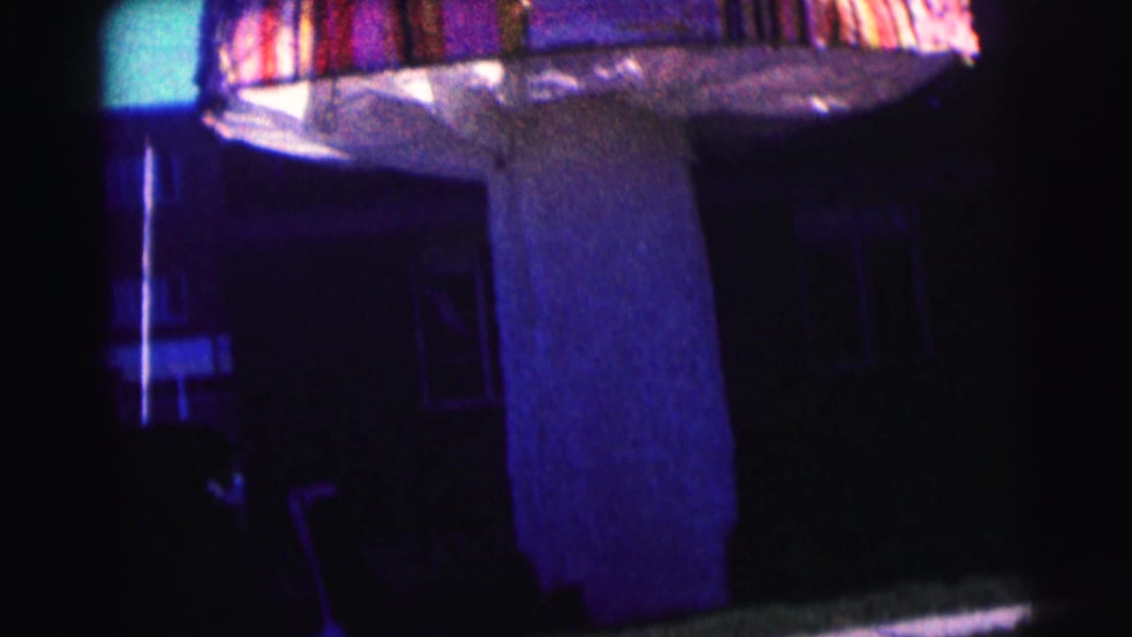 Mushroom-like canopy and central column in front of a dark building facade.