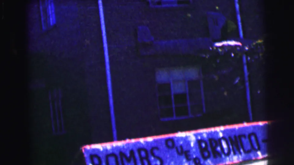 1963 8mm frame showing a Bowling Green University sign below a dark campus building exterior and windows.