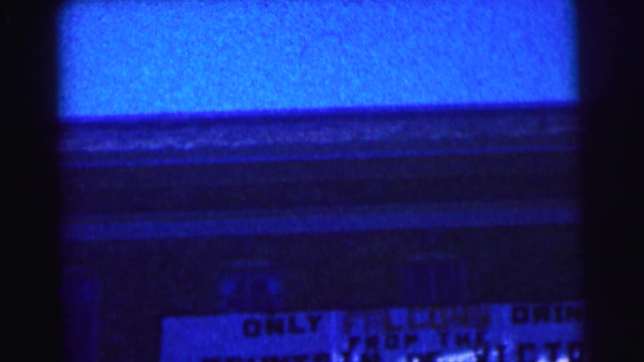 Blue-tinted nighttime building facade with part of a campus spirit sign visible near the bottom.