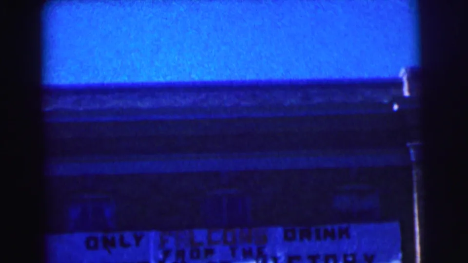 Blue-cast 8mm frame of a Bowling Green University exterior with part of the Falcons sign visible.