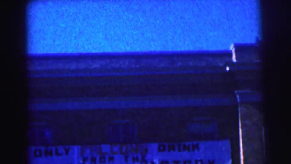 1963 campus exterior frame with a blue tint and a readable portion of the Falcons victory sign.
