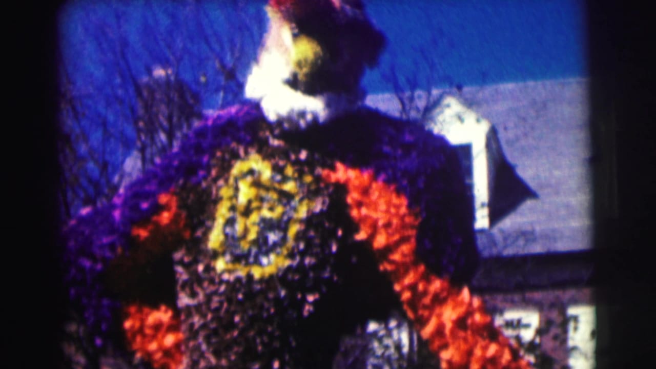 1963 Bowling Green University 8mm frame showing a large purple and orange floral birdlike figure near bare trees and a building roofline.