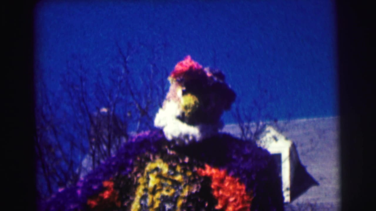 Upper part of a colorful oversized mascot or float under a deep blue sky.