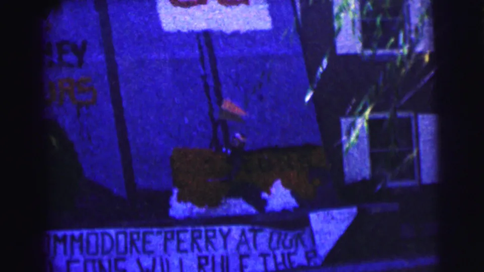1963 Bowling Green University home-movie frame showing hand-painted protest lettering near a dark building facade and window.