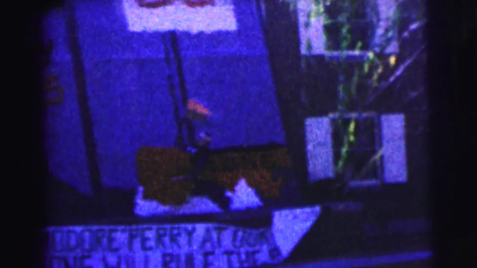 1963 Bowling Green University frame with partially readable hand-painted signs below a building window in low light.