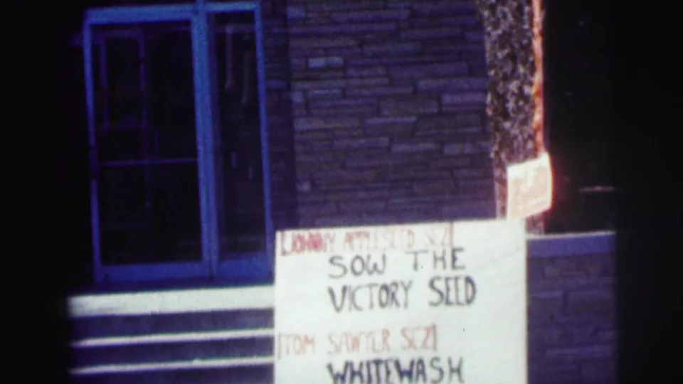Night exterior at Bowling Green University showing a sign reading Sow the Victory Seed near a brick entrance and steps.