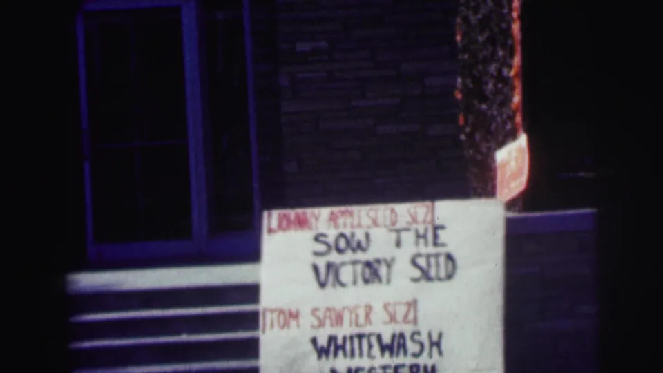 1963 campus night shot with a handmade sign mentioning Johnny Appleseed and Tom Sawyer Sizi outside a brick entrance.
