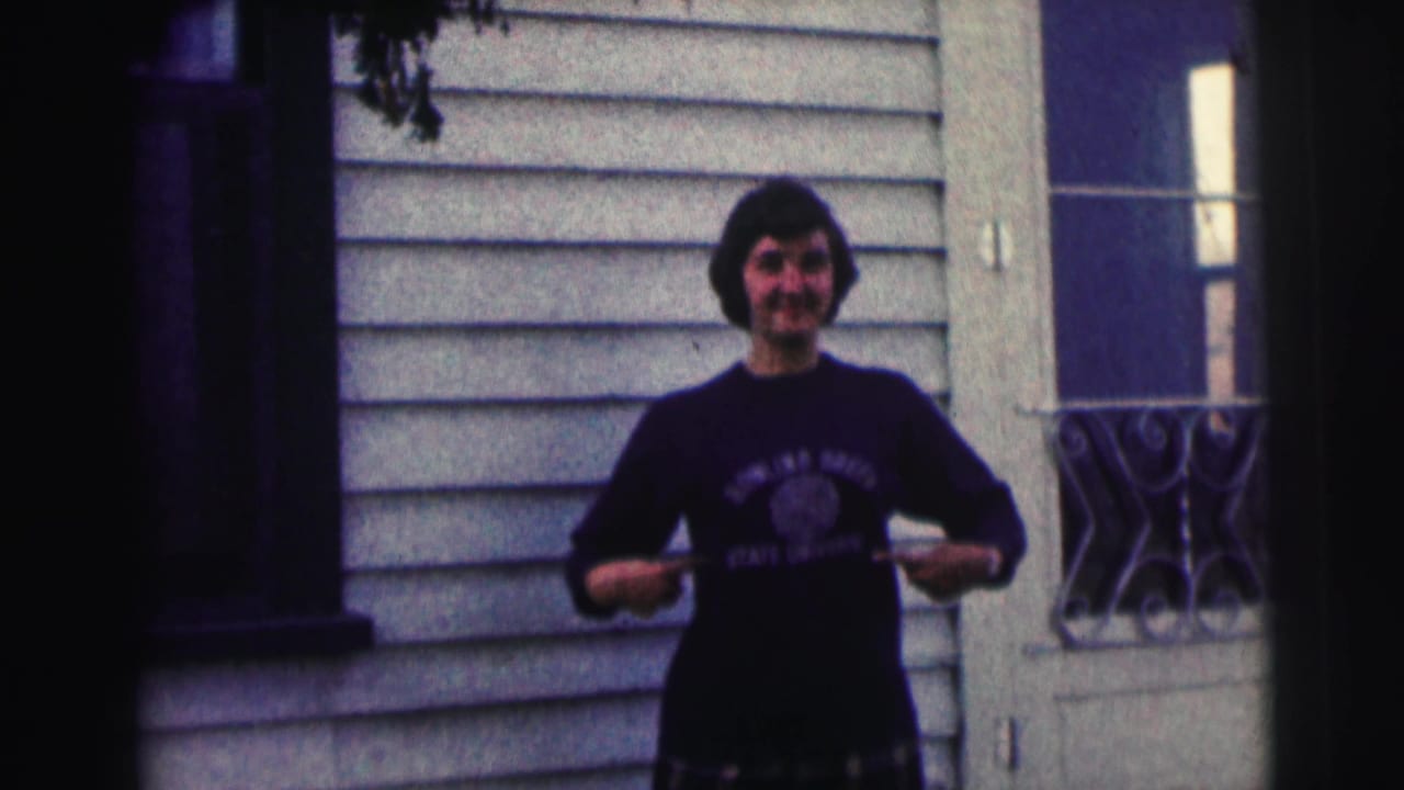 The woman smiles toward the camera and draws attention to the Bowling Green State University lettering on her sweatshirt.