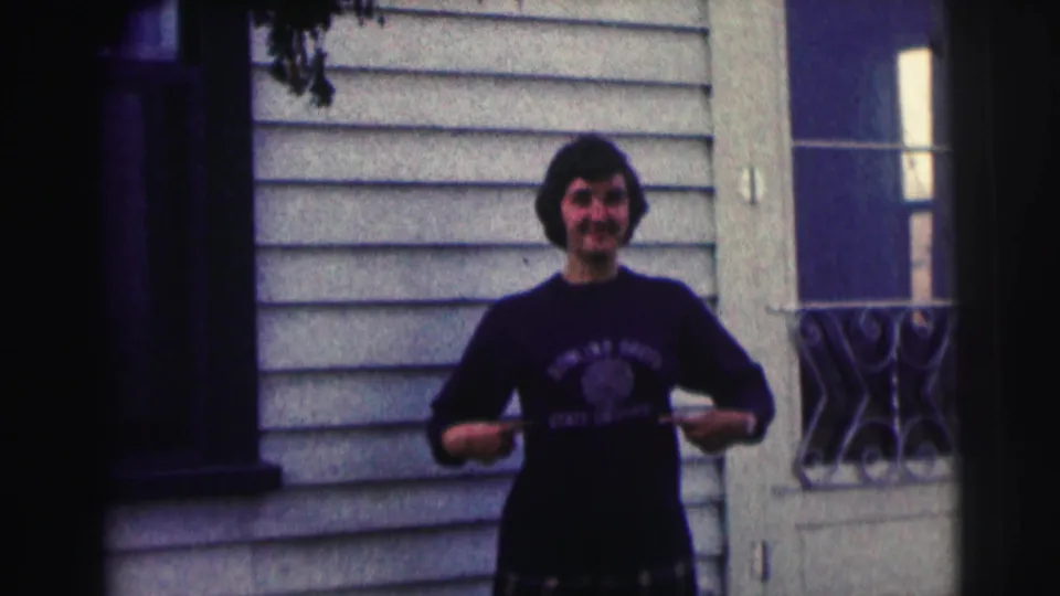 The woman smiles toward the camera and draws attention to the Bowling Green State University lettering on her sweatshirt.