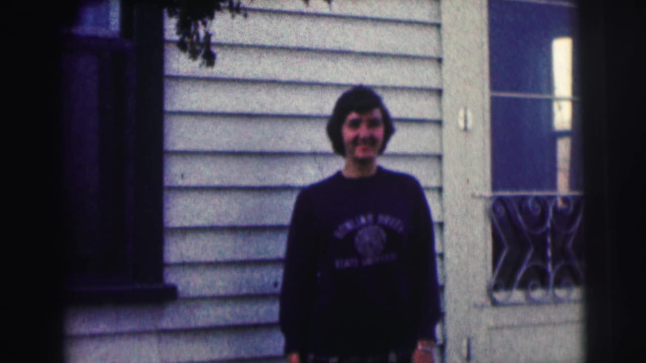 Smiling young man remains posed in front of a light-sided exterior with a window, wearing a Bowling Green State University sweatshirt.