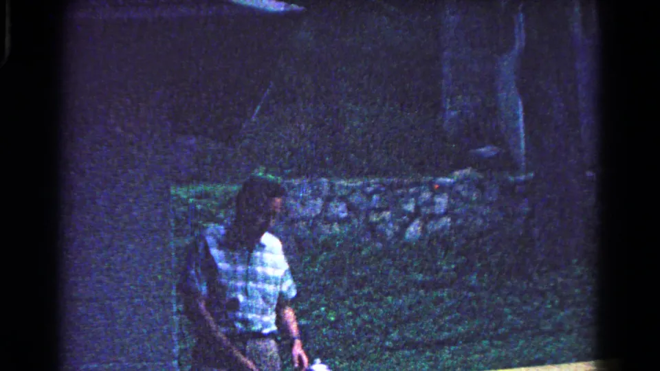 A man in a patterned shirt stands near a picnic table area in the 1963 Cold Springs campground home movie.