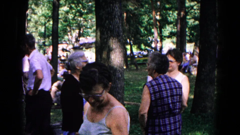 Older adults gather in a wooded Cold Springs, New York park in 1963, with women in summer tops and dresses and men in short-sleeve shirts.