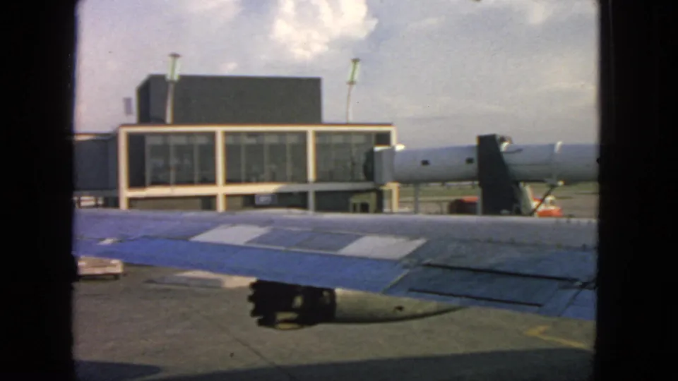 San Francisco airport tarmac in 1963, seen from a passenger window with the wing and terminal in view.