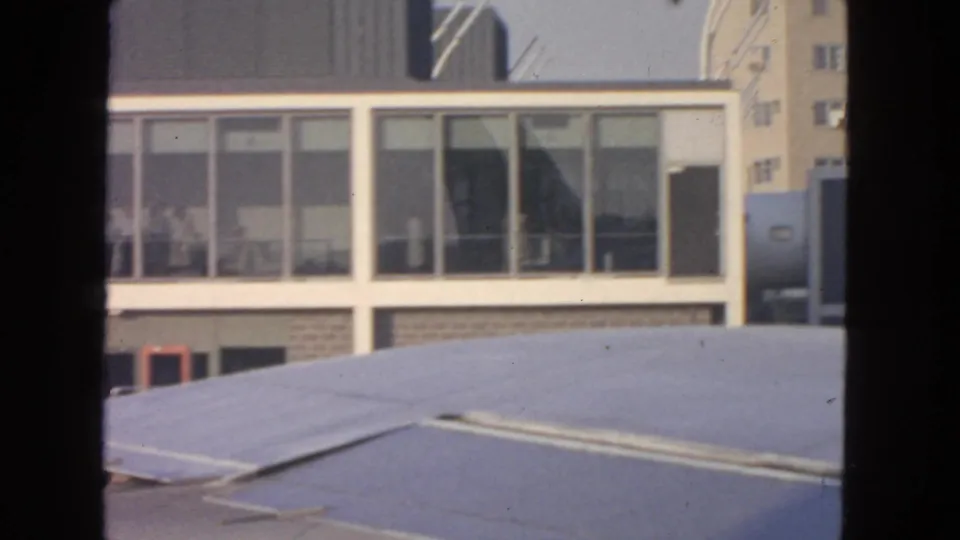 1963 San Francisco airport view from inside a plane, showing terminal windows, a light roof or wing surface, and film-edge borders.