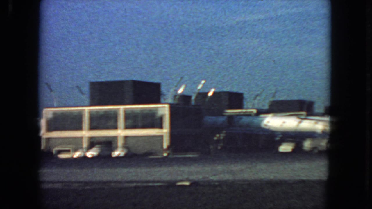 Parked airliner beside low terminal buildings on an airport tarmac.